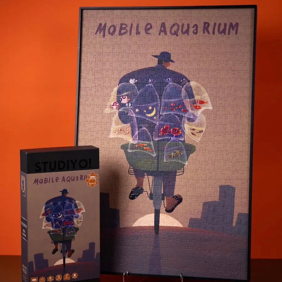 The puzzle artwork shows a surreal illustration titled 'MOBILE AQUARIUM' with a person in a hat surrounded by floating transparent fish tanks.